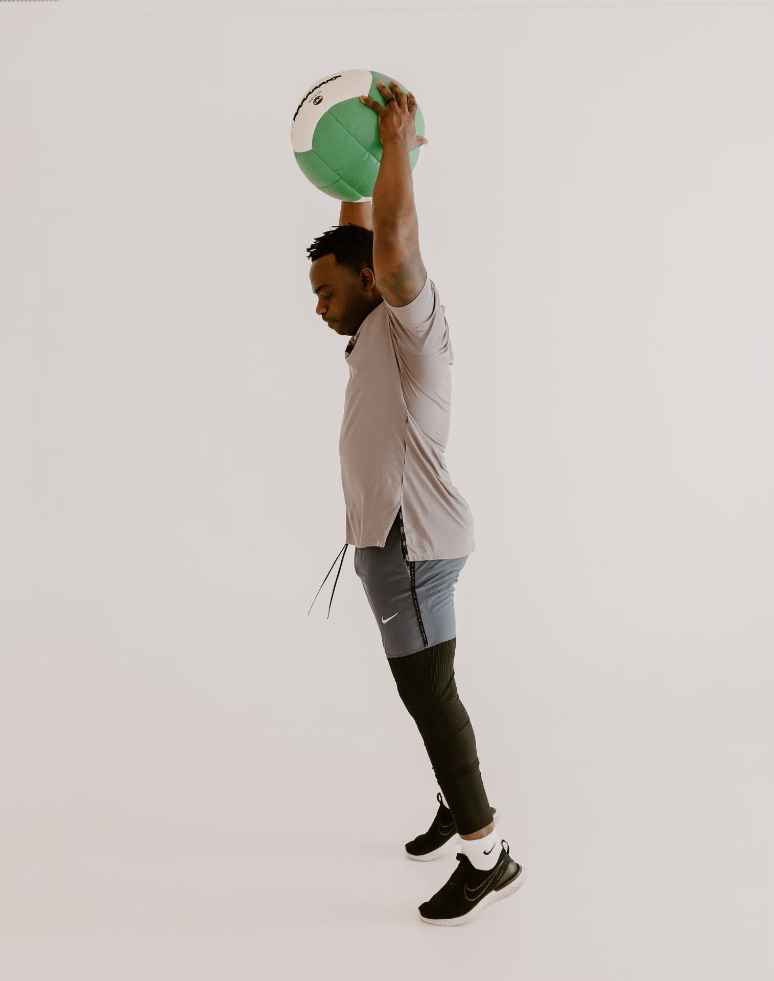 Coach Ben Birmingham performing an overhead medicine ball slam during a training session in Edmond, OK